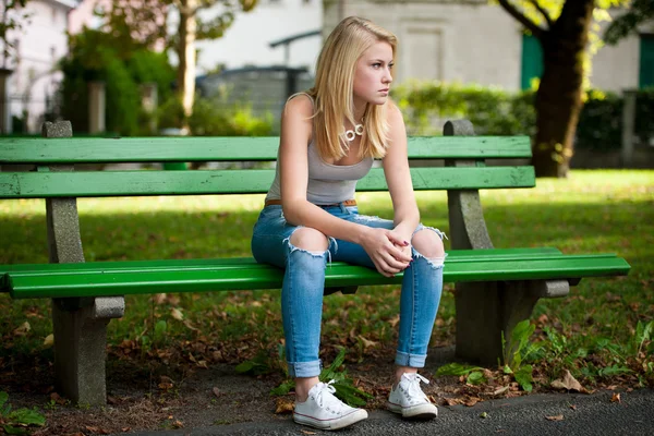 Beautiful blonde woamn rests on a bench in park — Stock Photo, Image