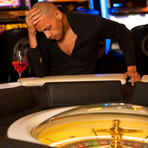Young man playing roulette in casino betting and loosing money — Stock Photo, Image