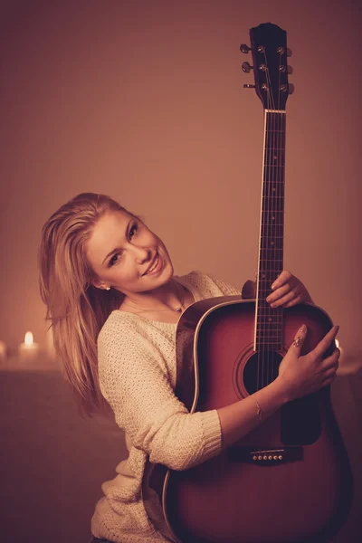 Mujer rubia joven tocando la guitarra a la luz de las velas — Foto de Stock