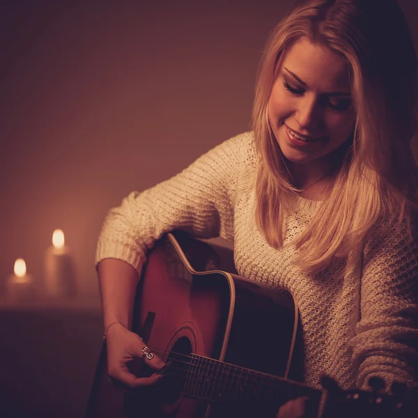 年轻的金发女子，在烛光下弹吉他 — 图库照片