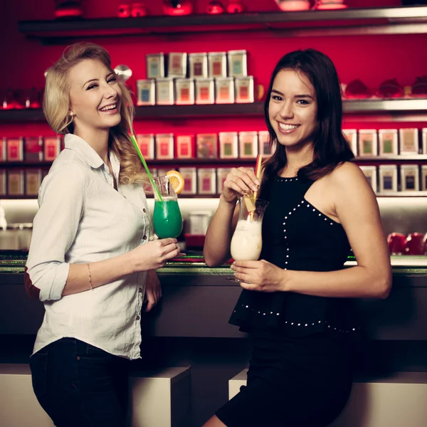 Две красивые женщины пьют коктейль в ночном клубе и пьют — стоковое фото