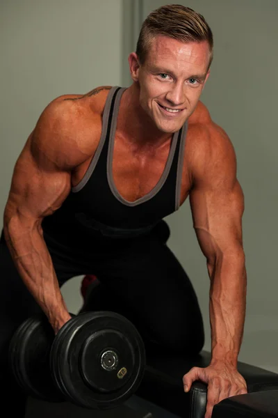 Knappe jongeman uit te werken met halters in fitness - krachttraining — Stockfoto