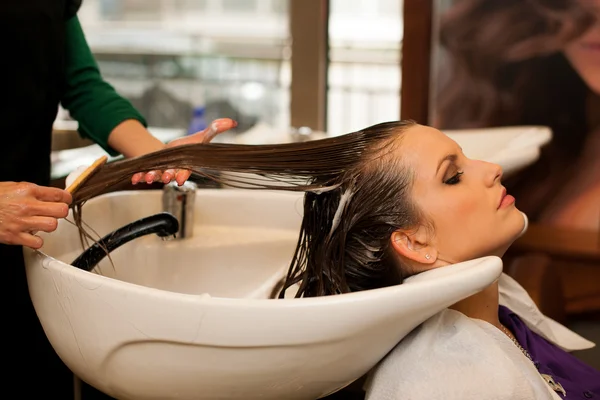 Парикмахер делает уход за волосами для клиента в салоне — стоковое фото
