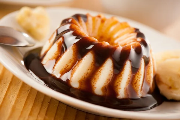 Vanilla pudding with choccolate syrup and banana slices served on white plate — Stock Photo, Image