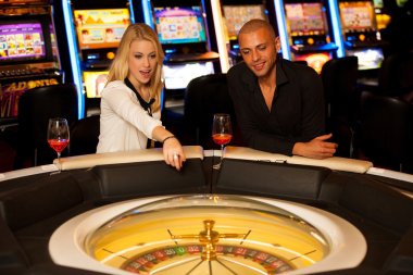 Young couple playing roulette in casino betting and winning clipart