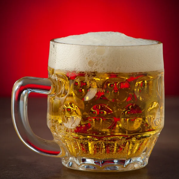 Two glasses of beer on a stone table over red background — Stock Photo, Image