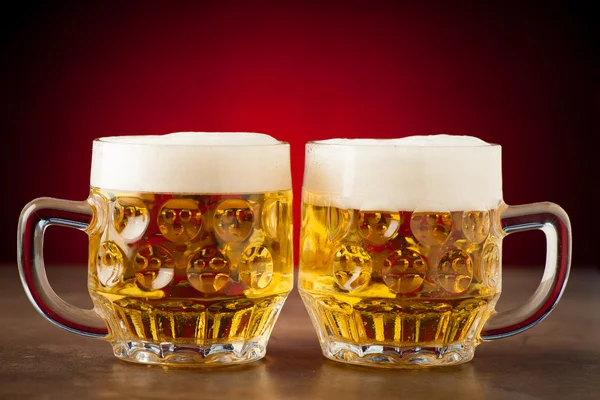 Two glasses of beer on a stone table over red background — Stock Photo, Image