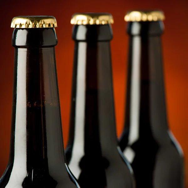 Three bottles of beer over brown background — Stock Photo, Image