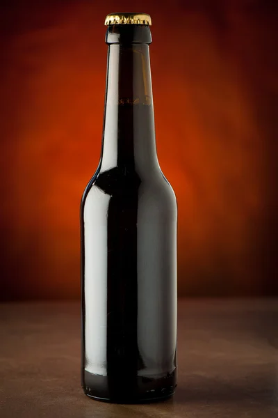 Bottle of beer on a stone table over brown background — Stock Photo, Image