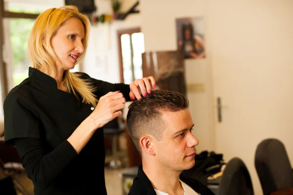 Female hairdresser cutting hair of smiling man client at beauty — Stock Photo, Image
