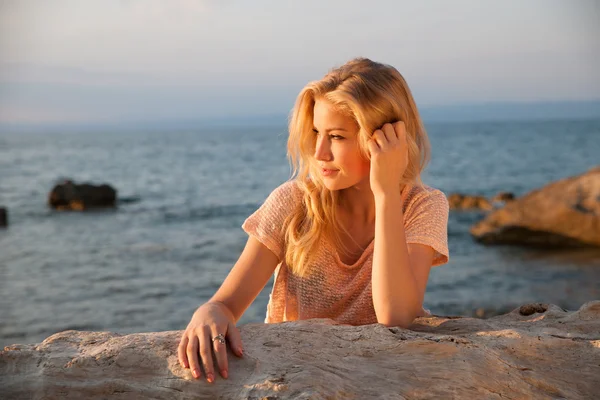 Mooie jonge blonde vrouw rusten op een strand in de schemering in vroeg — Stockfoto
