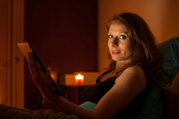 Pretty woman surfing web on a tablet in bed before sleeping — Stock Photo, Image