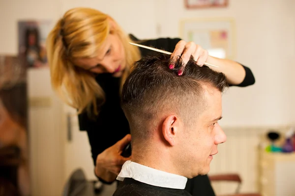Женщина парикмахер стрижет волосы улыбающегося мужчины клиента на красоту — стоковое фото