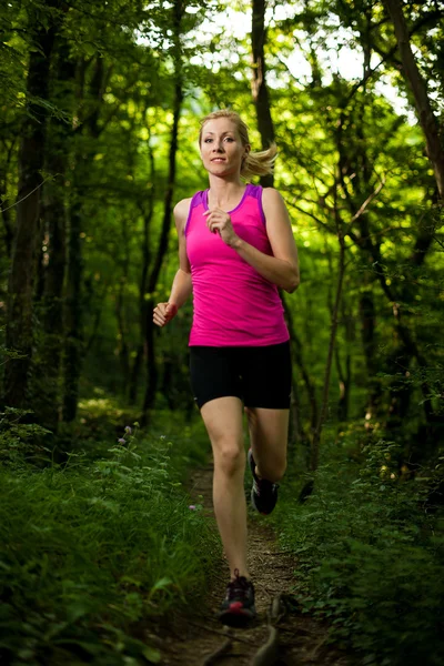 Bella giovane donna corre sul sentiero forestale — Foto Stock