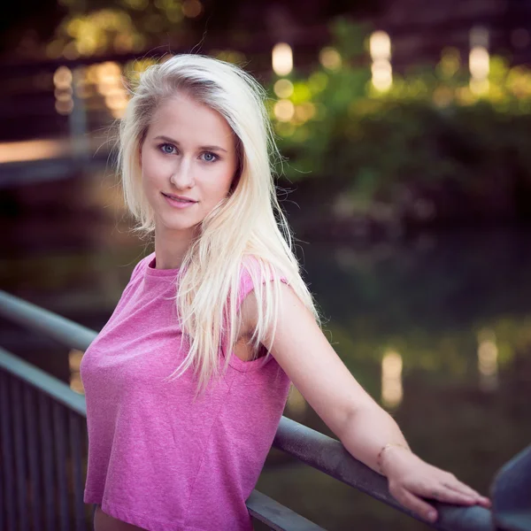 Mooie jonge blonde vrouw rusten op een bankje in de schemering in de zomer — Stockfoto