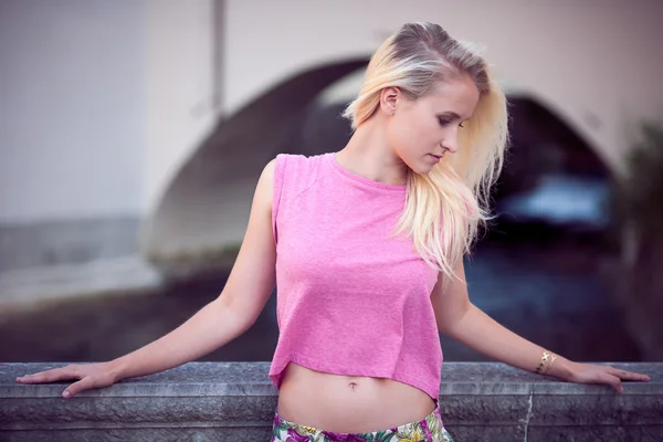 Beautiful young blonde woman resting on a bench at dusk in summer — Stock Photo, Image