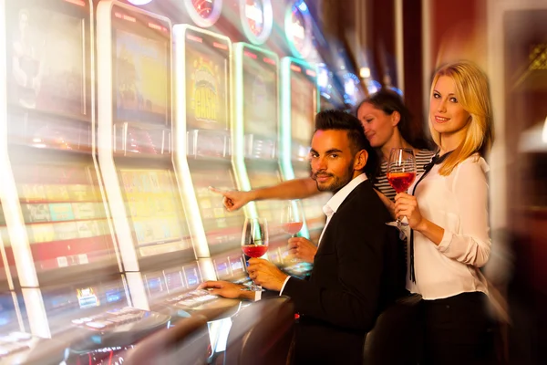 Чотири молоді люди грають в ігрові автомати в казино — стокове фото