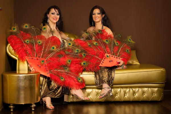 Two belly dancers sitting on a golden sofa while preforming on stage — Stock Photo, Image