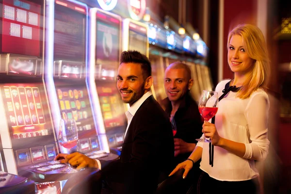 Quatre jeunes qui jouent aux machines à sous dans le casino — Photo