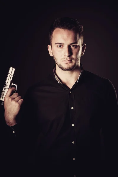 Dangerous man with a gun standing in dark — Stock Photo, Image