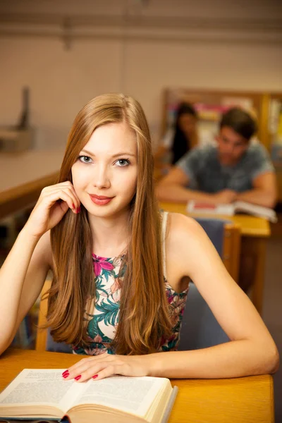 Beautiful young woman student in library — Stock Photo, Image