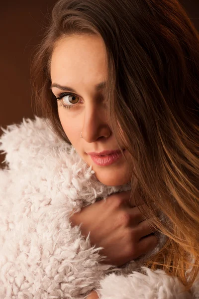 Bailarina morena posando en un abrigo blanco esponjoso delante de fondo oscuro —  Fotos de Stock