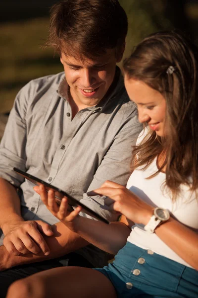 Jeune couple s'amuser sur un banc dans le parc tout en socialisant ove — Photo