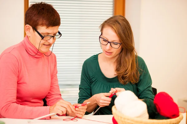 Women knitting with red wool. Eldery woman transfering her knowl — Stock Photo, Image