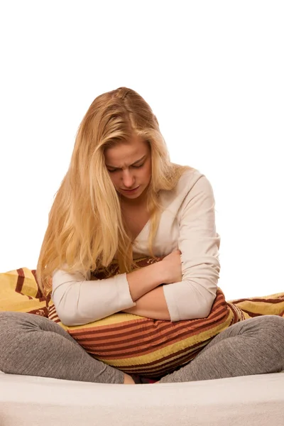 Mujer sentada en la cama sosteniendo el vientre debido al dolor de estómago —  Fotos de Stock