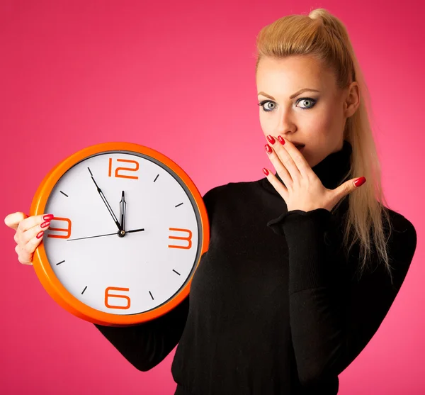 Besorgte Frau mit großer orangefarbener Uhr, die Verzögerung, Eile, Nervosität gestikuliert Stockfoto