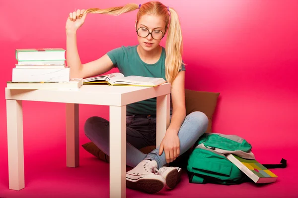 Speelse schoolmeisje met grote brillen geconcentreerd in het lezen van b — Stockfoto