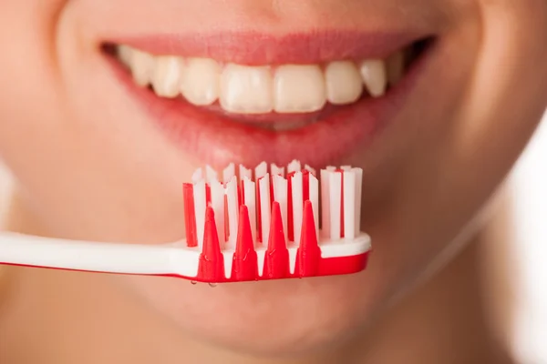 Mujer sosteniendo cepillo de dientes delante de los dientes promoviendo la boca hygie — Foto de Stock