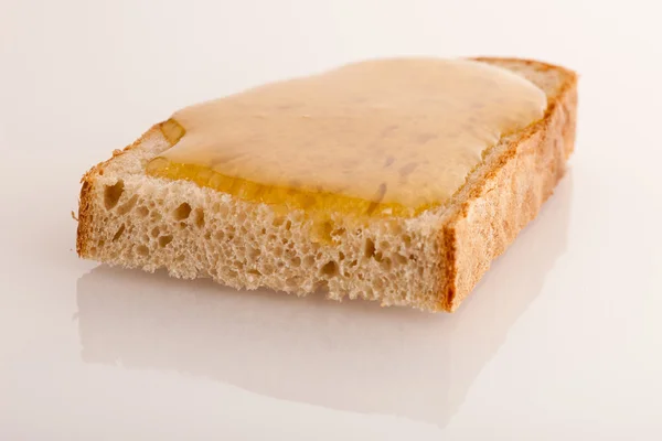 Doce mel dourado pegajoso em uma fatia de pão fresco . — Fotografia de Stock