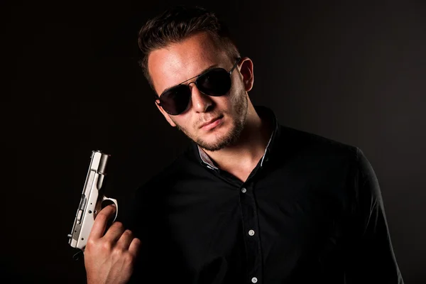 Dangerous man with a gun and sunglasses — Stock Photo, Image