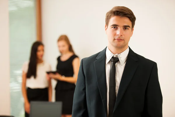 Молодой бизнесмен, стоящий на первом плане с коллегами в Б — стоковое фото