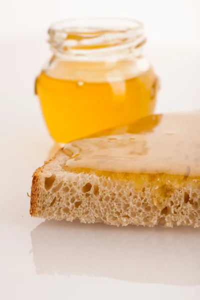 Mel dourado pegajoso doce em uma fatia de pão fresco e um copo — Fotografia de Stock