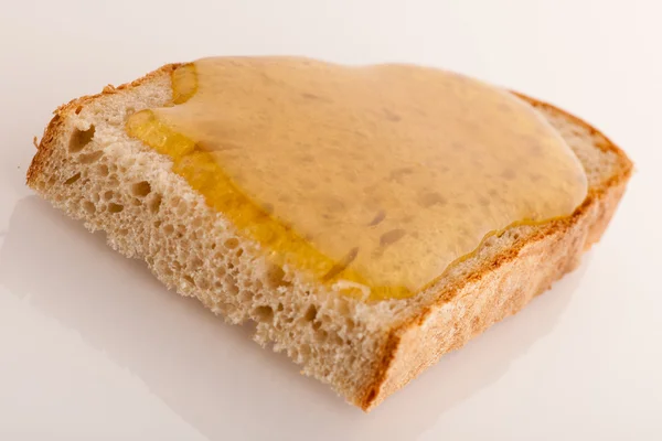 Doce mel dourado pegajoso em uma fatia de pão fresco . — Fotografia de Stock