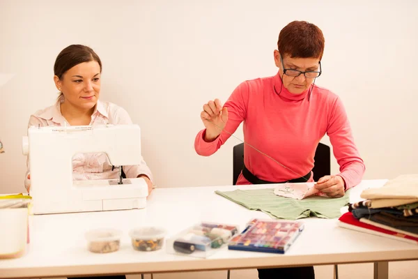 Women are sewing on handcraft workshop. They are teaching each o — Stock Photo, Image