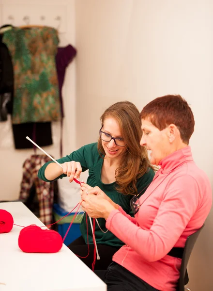 Women knitting with red wool. Eldery woman transfering her knowl — Stock Photo, Image