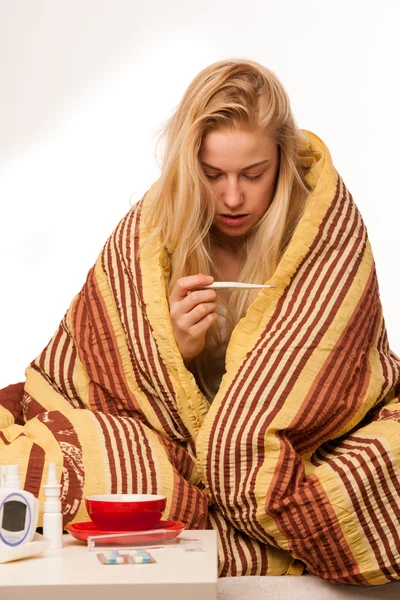 Sick woman sitting on bad wrapped in a blanket feeling ill, has — Stock Photo, Image