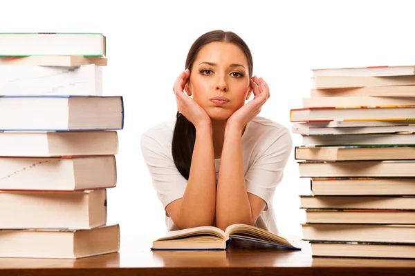 Sick and tired woman reading behind the table between two pile o — Stock Photo, Image