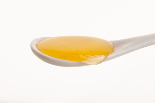 Witte cheramic lepel gevuld met zoete gouden honing. — Stockfoto