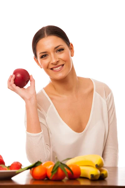 Mujer detrás de la mesa llena de fruta fresca y saludable . — Foto de Stock