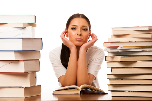 Sick and tired woman reading behind the table between two pile o — Stock Photo, Image