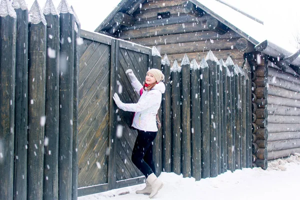 Rusya, Tula. 9 Ocak 2021. Ahşap bir evin arka planında güzel bir turistin portresi ve kışın bir çit..
