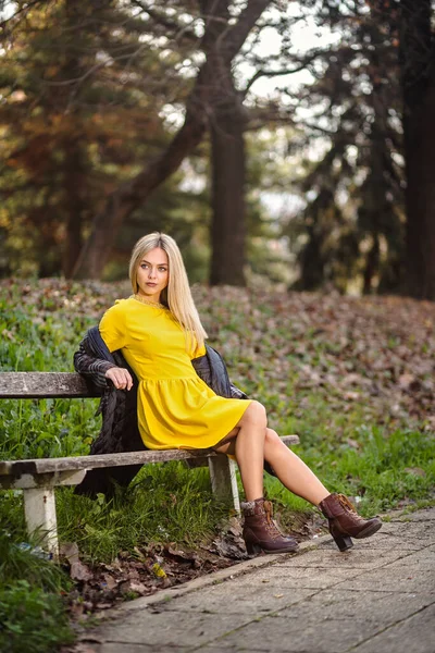 Mulher Loira Vestido Amarelo Casaco Está Sentado Banco Parque — Fotografia de Stock