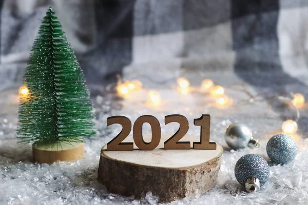 Güzel yeni yıl kartpostalı. Ahşap numaralar 2021, Noel baloları ve Noel ağacı şenlikli bulanık bir arka plana karşı. Yılbaşı tatili geçmişi. Kapat, seçici odak, boşluğu kopyala.