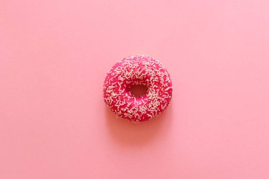 Fotokopi alanı olan pembe arkaplana yakın plan serpiştirilmiş pembe donut. Düz yatış, üst görünüm.