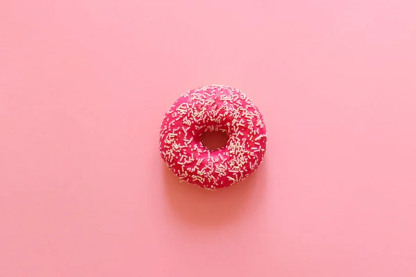 Fotokopi alanı olan pembe arkaplana yakın plan serpiştirilmiş pembe donut. Düz yatış, üst görünüm.