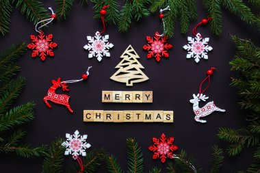 Noel ağacı dalları, kar taneleri, Noel oyuncakları ve ahşap harflerle süslü Noel kartpostalı. Mutlu Noeller. Şenlikli, tatil konsepti. Üst manzara, düz uzanma.